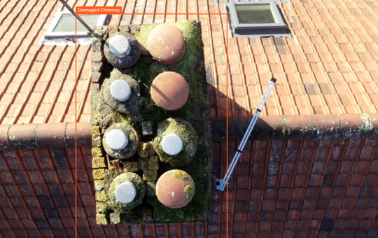 An aerial shot of a roof, with a cracked chimney outlined in red