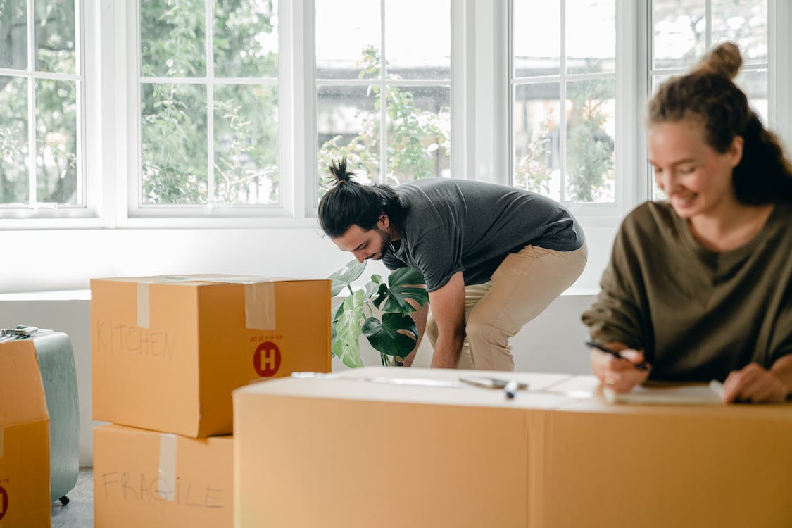 Man and woman unpacking with 5 large cardboard boxes in front of them