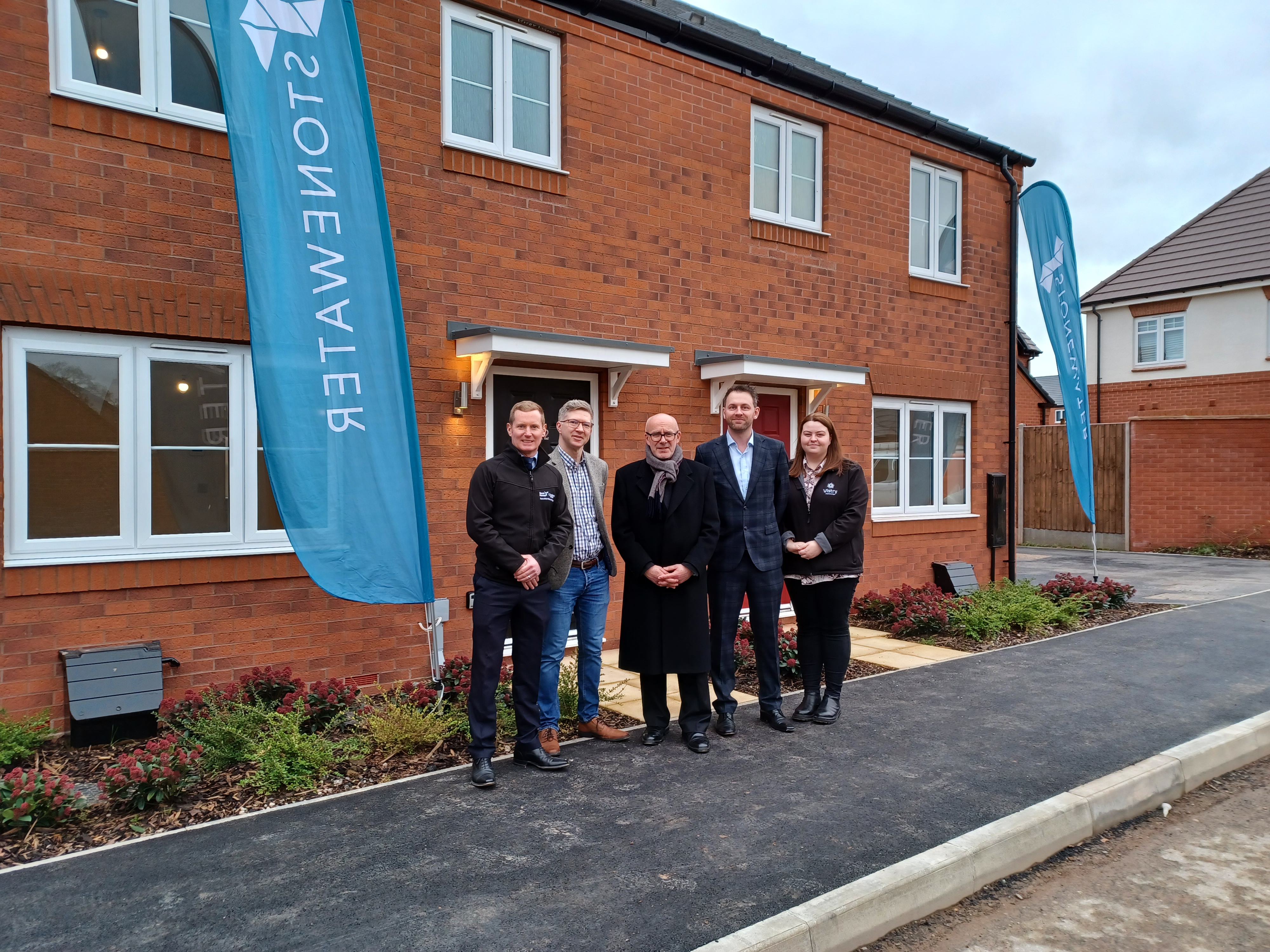 5 people stood outside new-build home with Stonewater banners