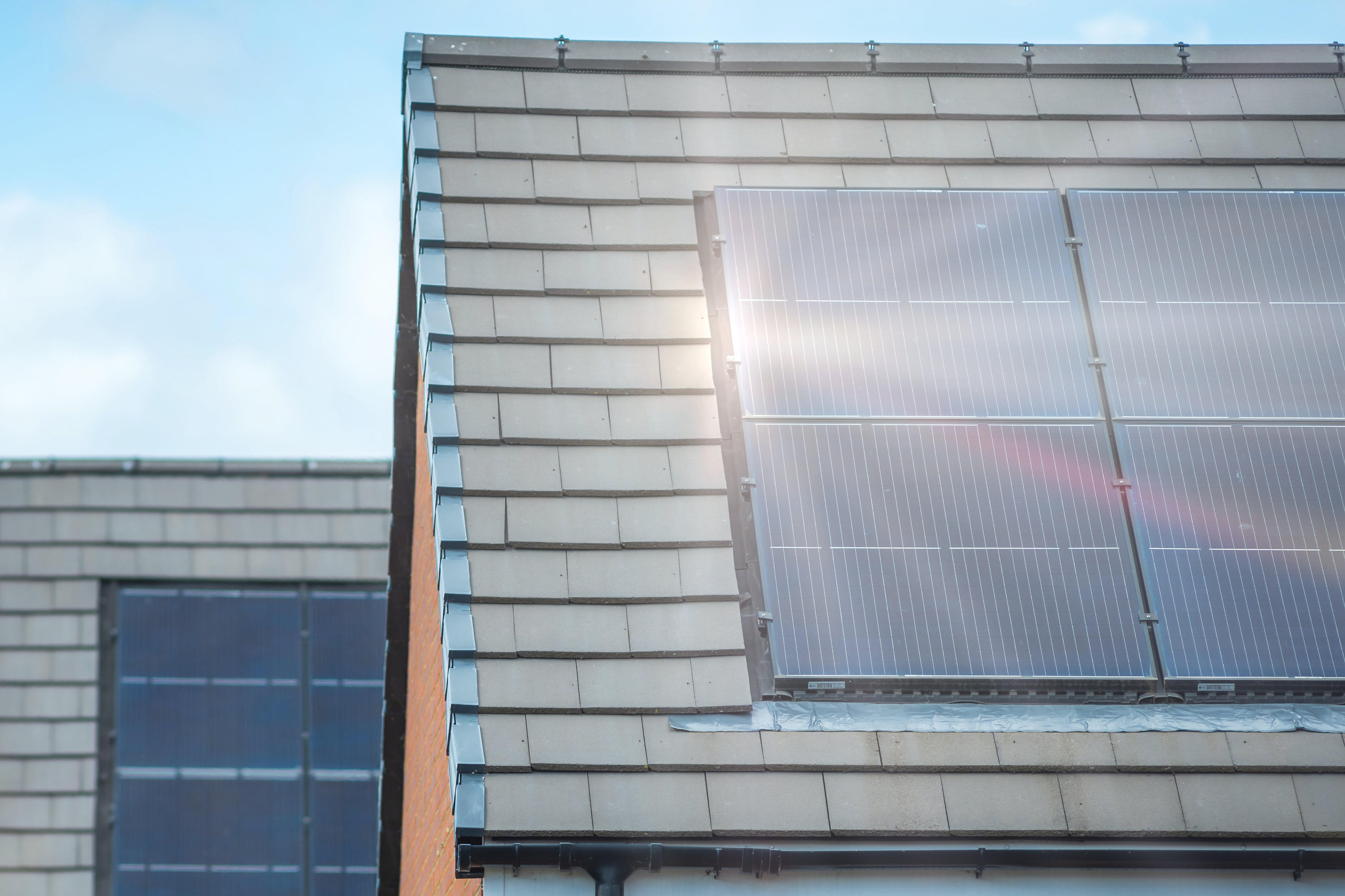 Close-up of two houses with solar panels on roofs, sun shining on them