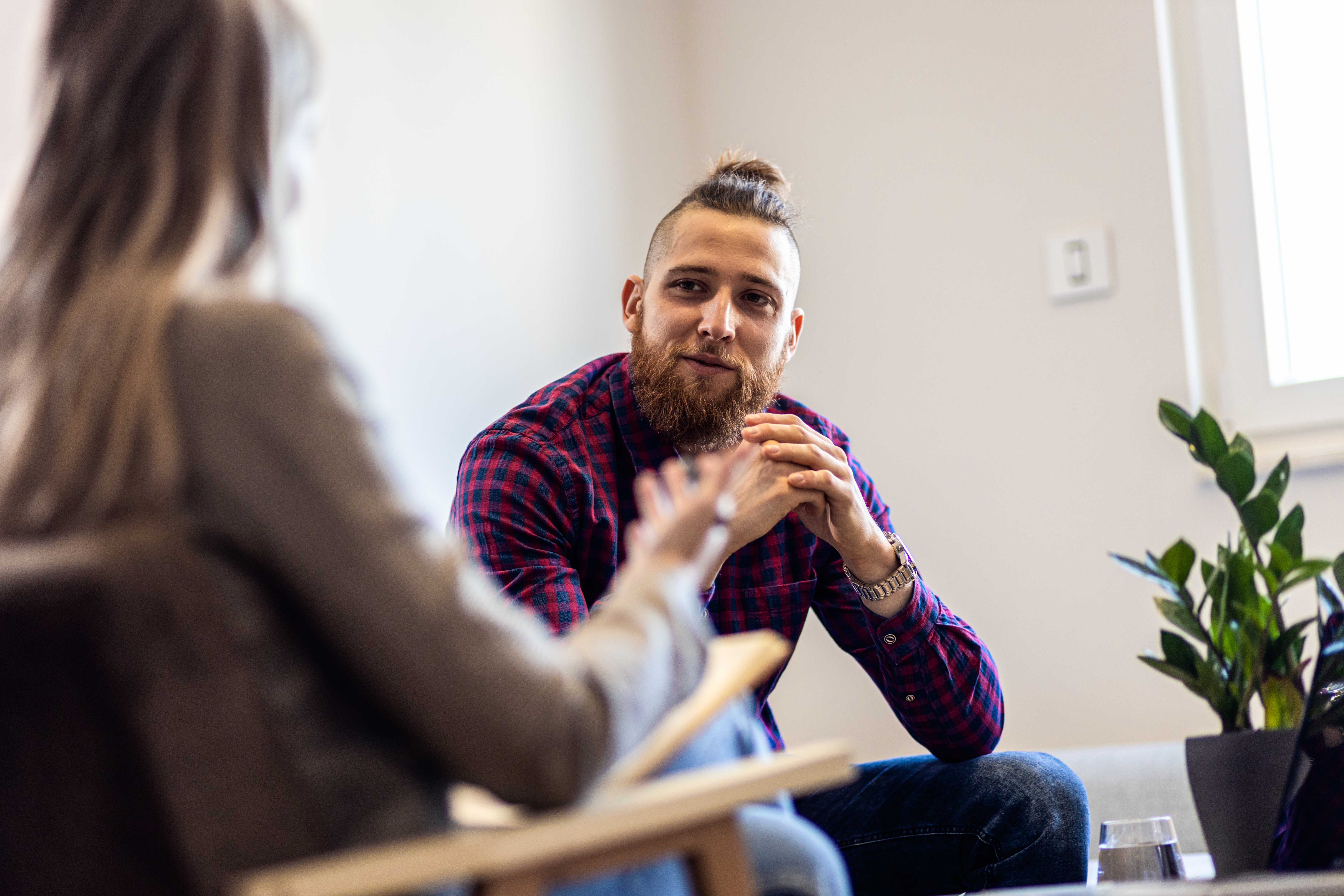 Man in checked shirt leaning forward talking to counsellor