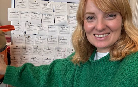 A woman smiling in front of a message board