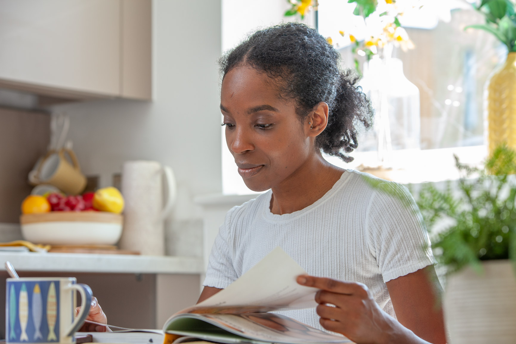 Woman in kitchen smiling and reading book