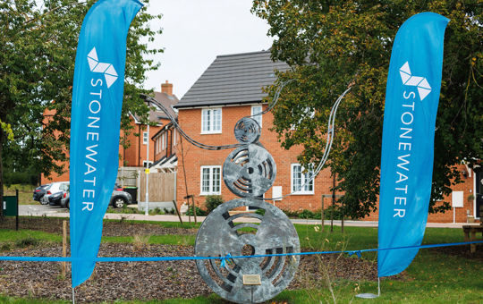 Public art piece next to Stonewater banners, a collection of metal works in the shape of film reels