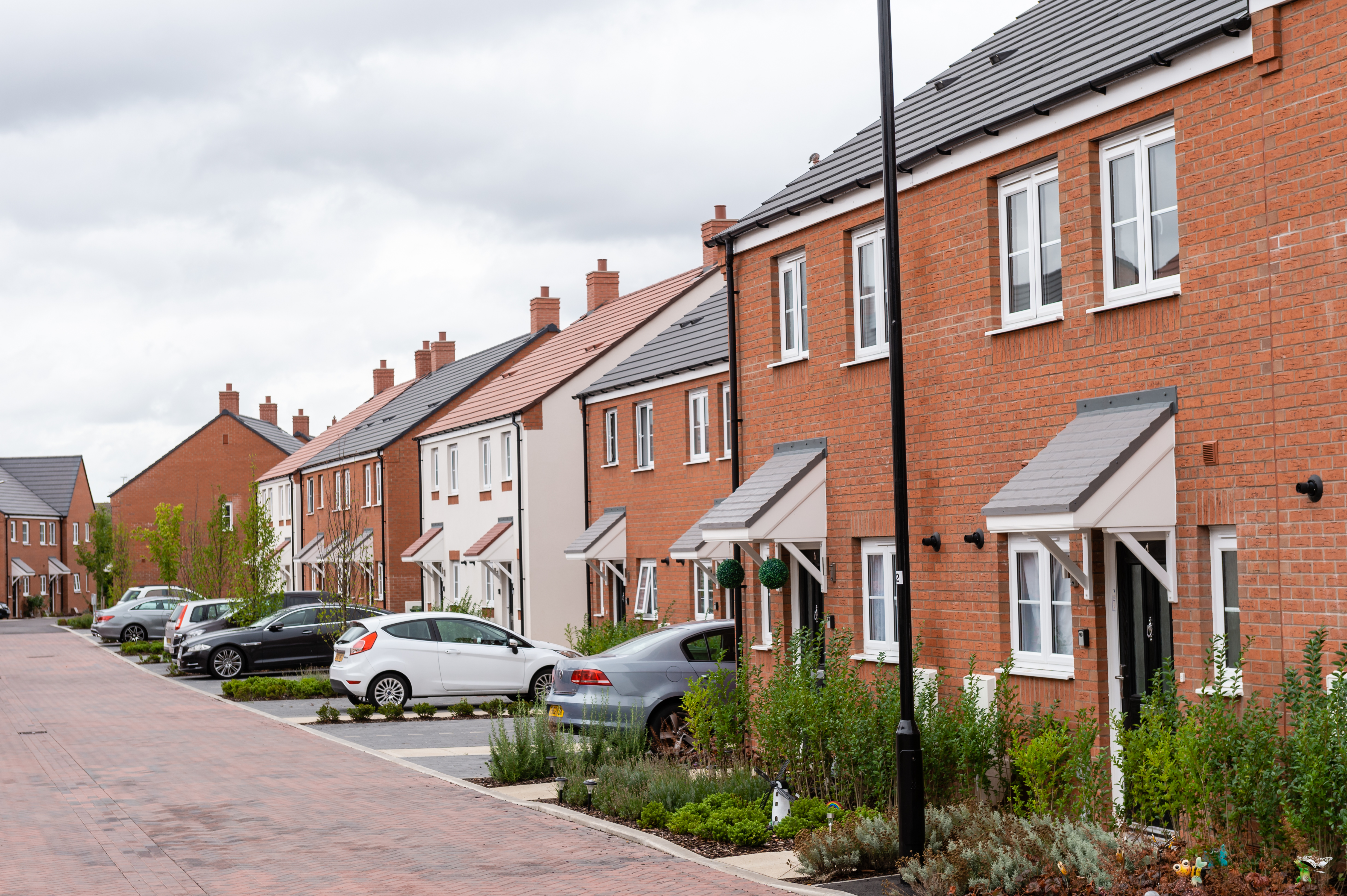 Street shot of a row of terraced new-build houses with cars parked outside