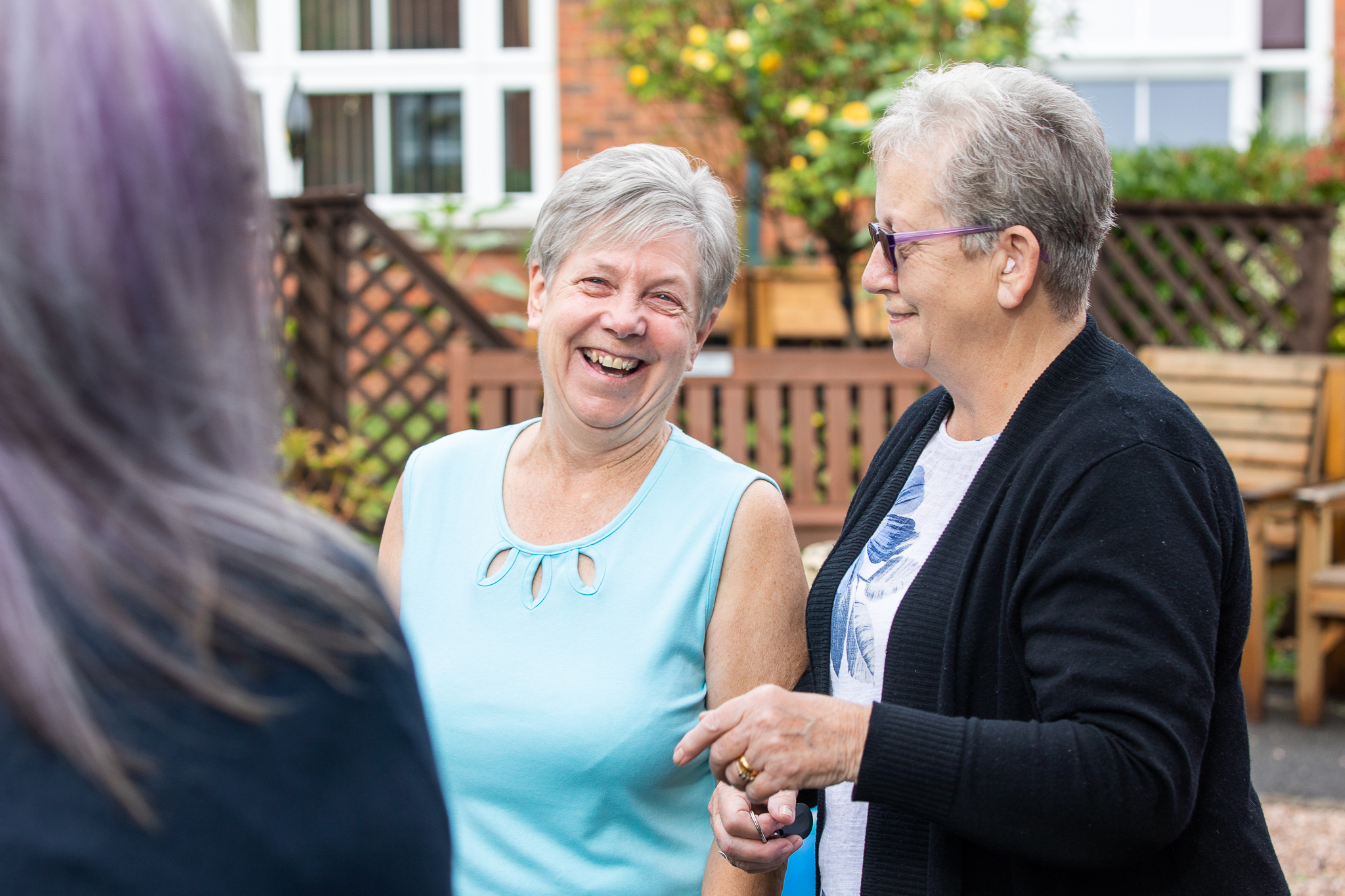 Two older ladies facing camera and smiling in retirement living scheme gardens