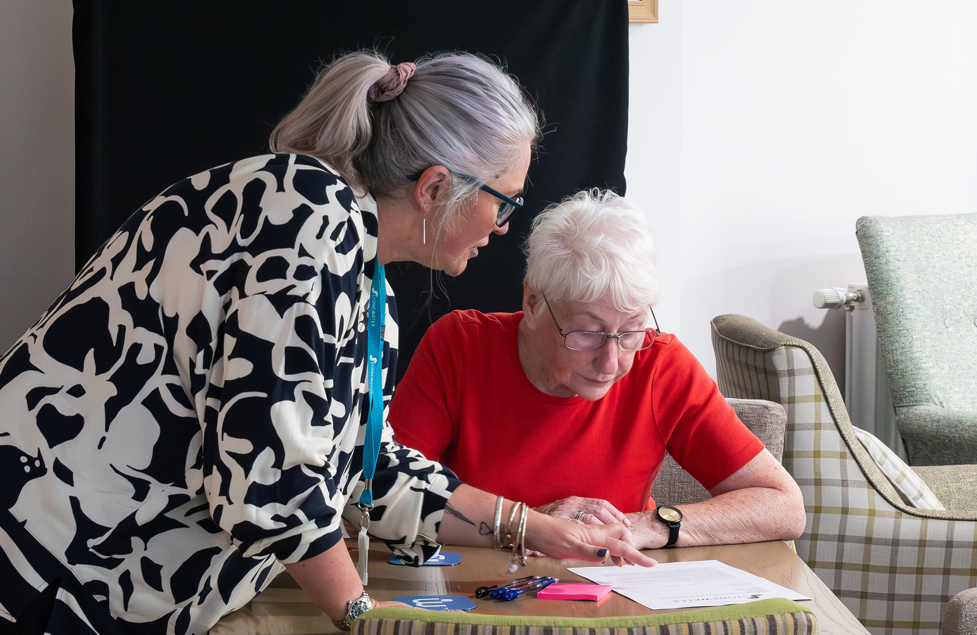 Two women talking whilst looking at a paper form