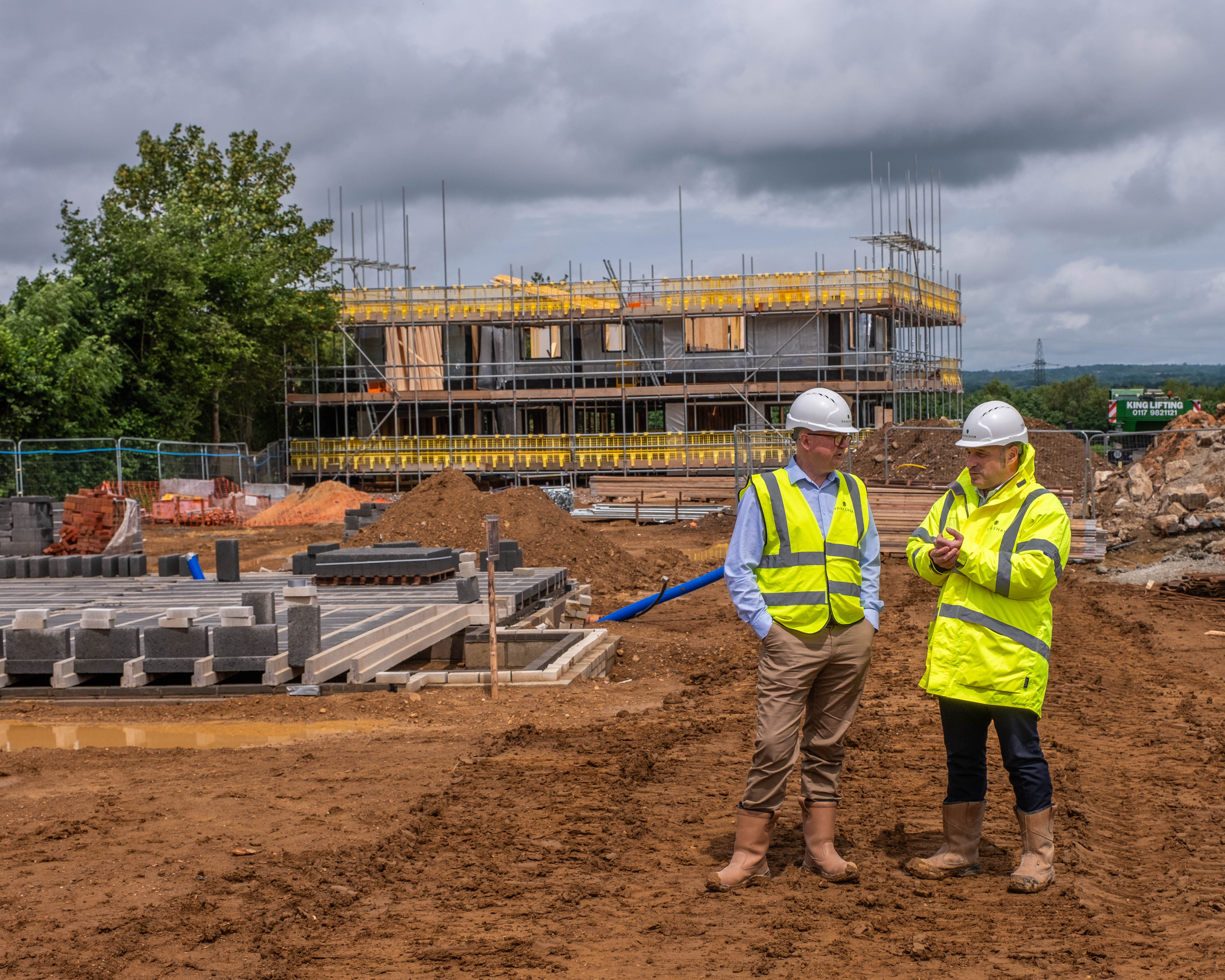 Two men in hi-vis jackets and hard hats talking on building site