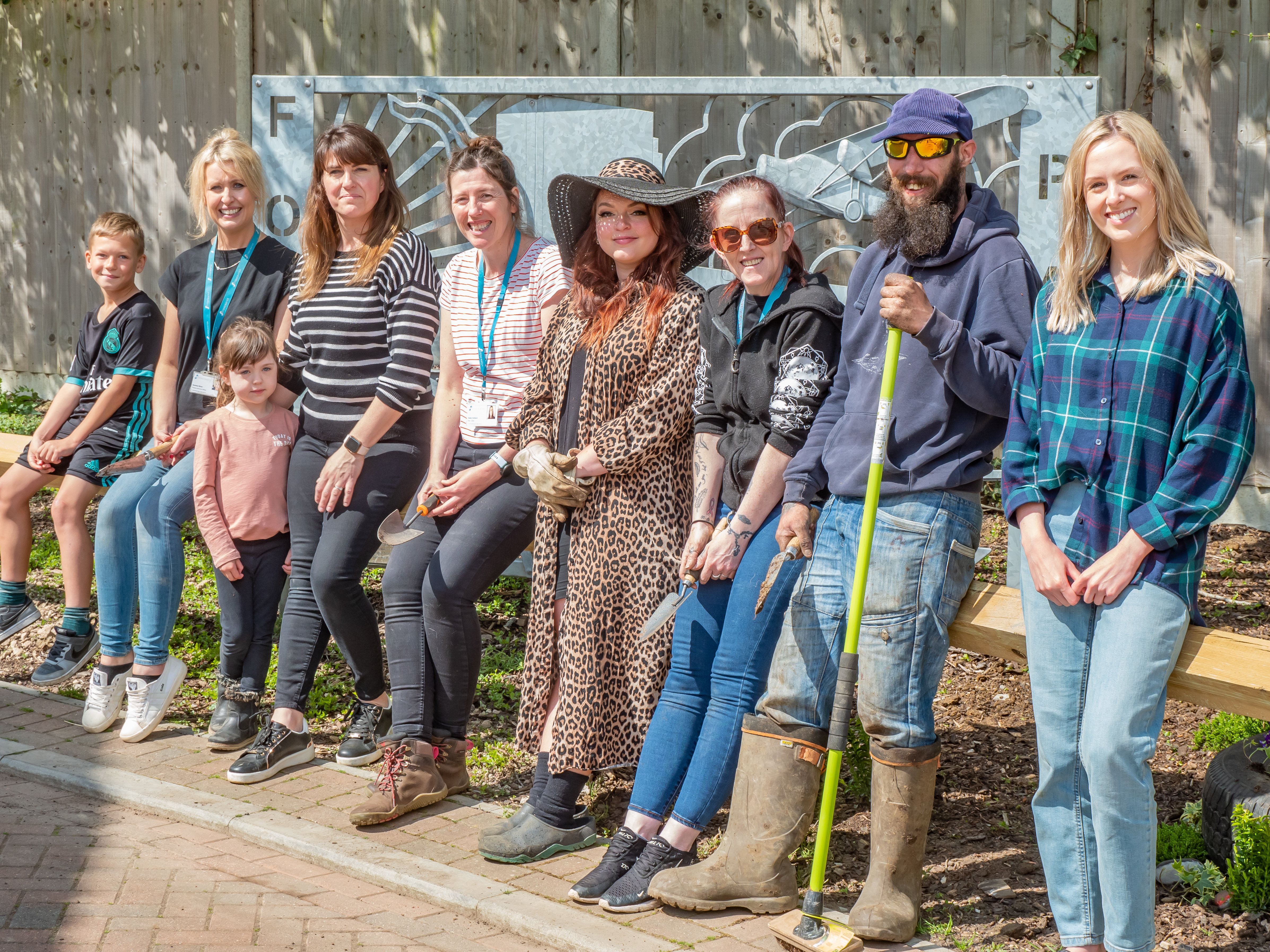 Group shot of community champions stood up holding gardening equipment