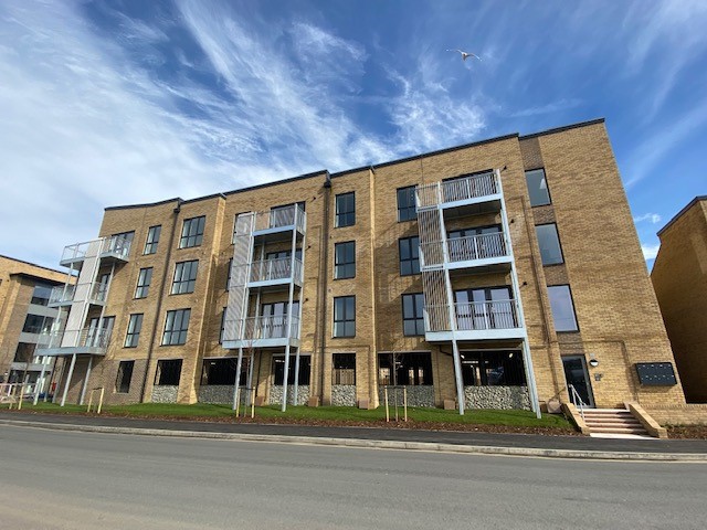 Street shot of Stonewater flats with balconies against a blue cloudy sky