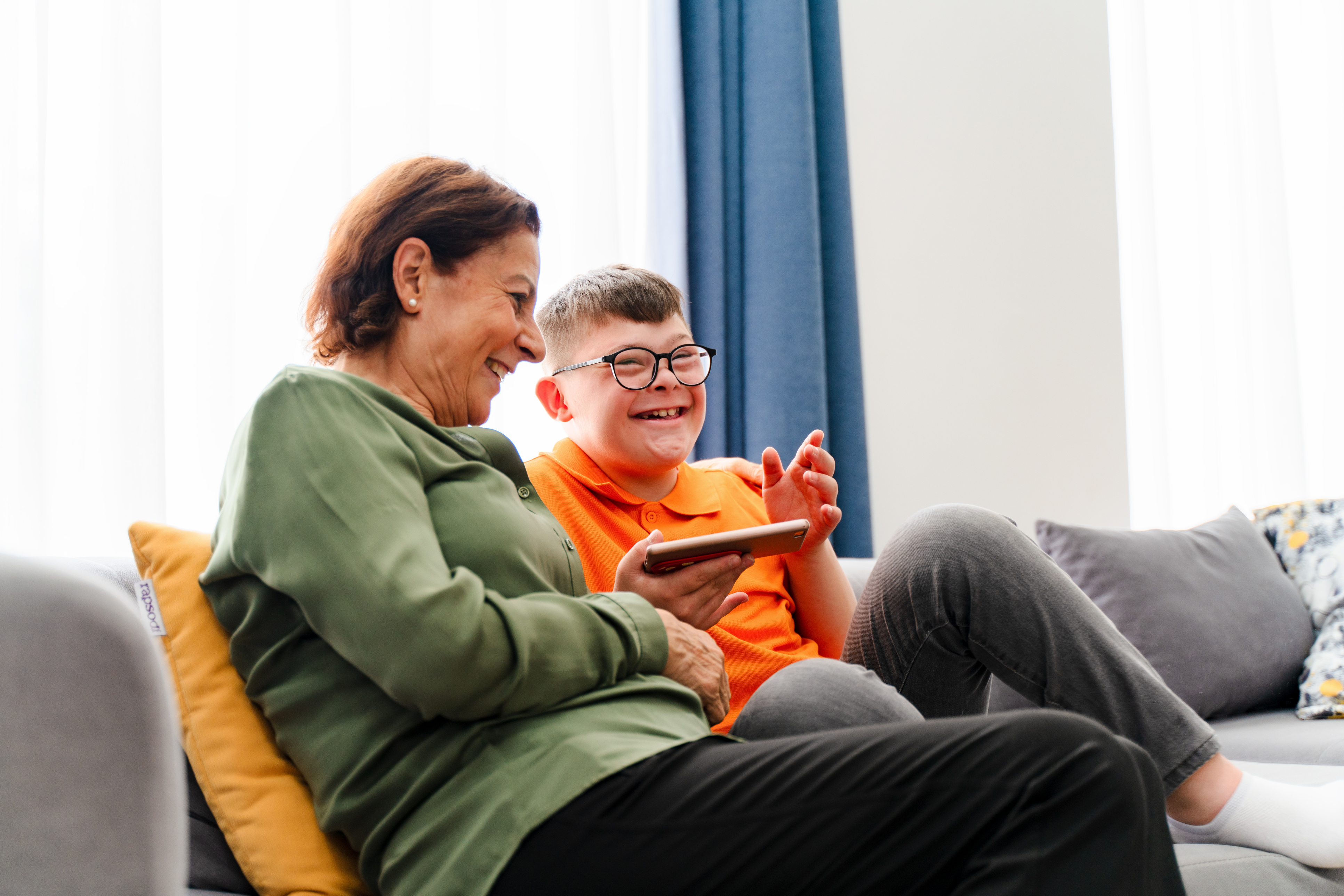 Woman and boy sat on sofa laughing