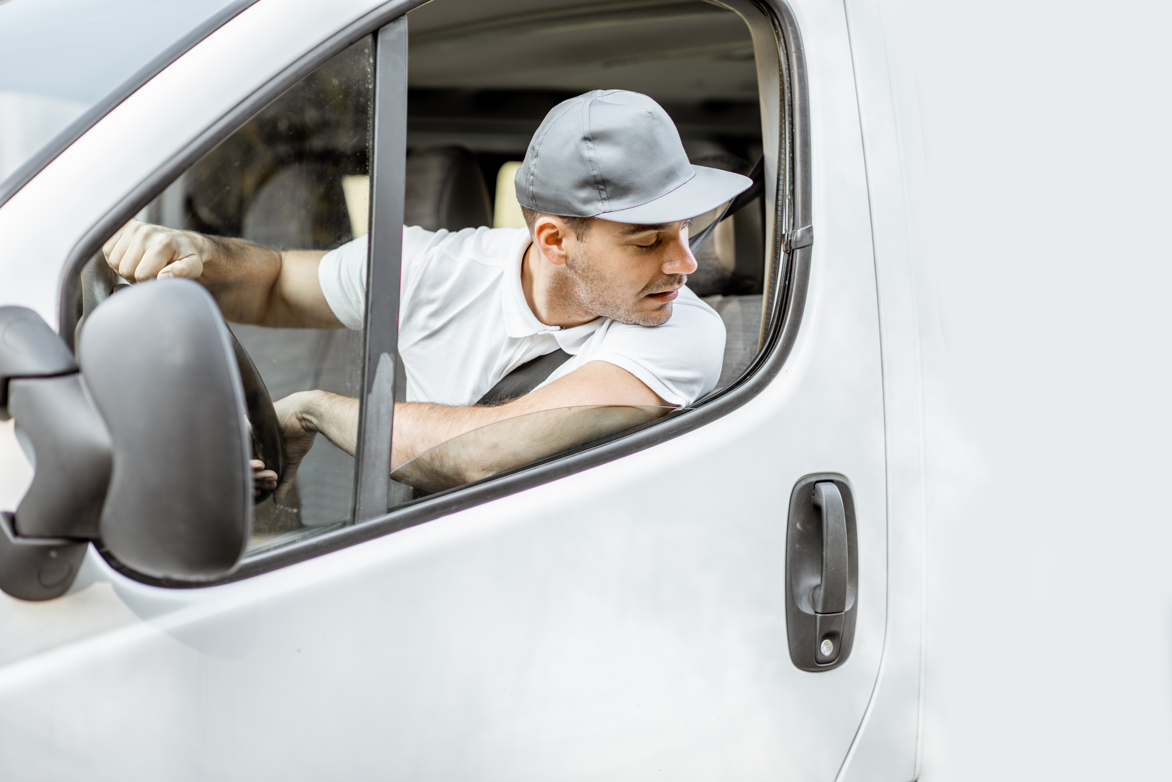 Close-up of a man in a white van looking backwards out the window to reverse