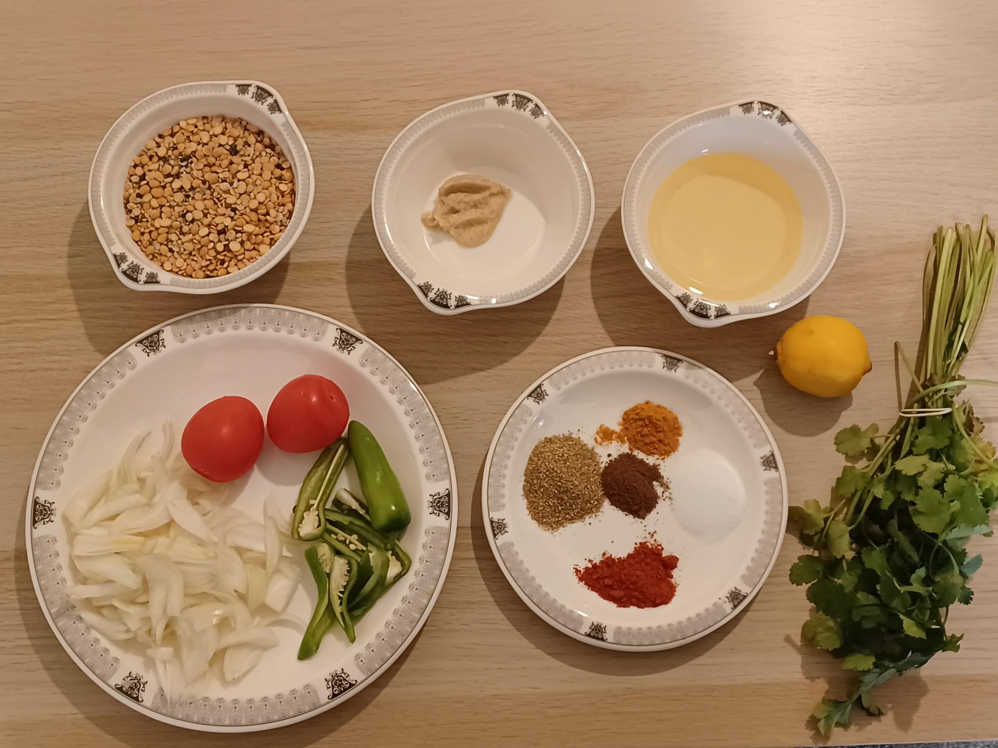 5 dishes viewed from above with ingredients for Daal soup on them; spices, tomato, onion, lentils.