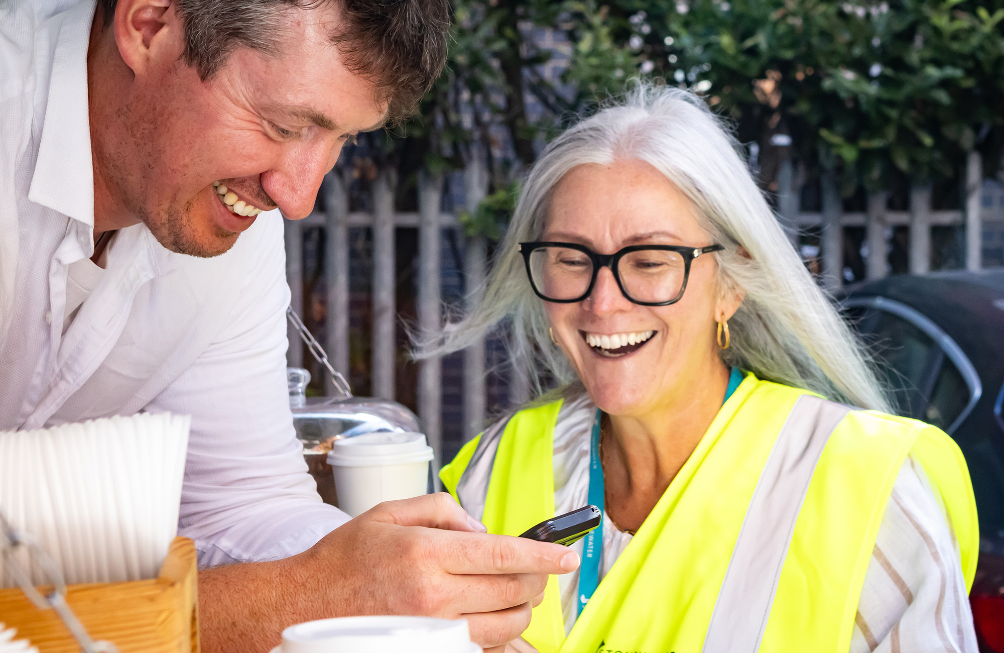 Man and a woman laughing and looking at a phone screen