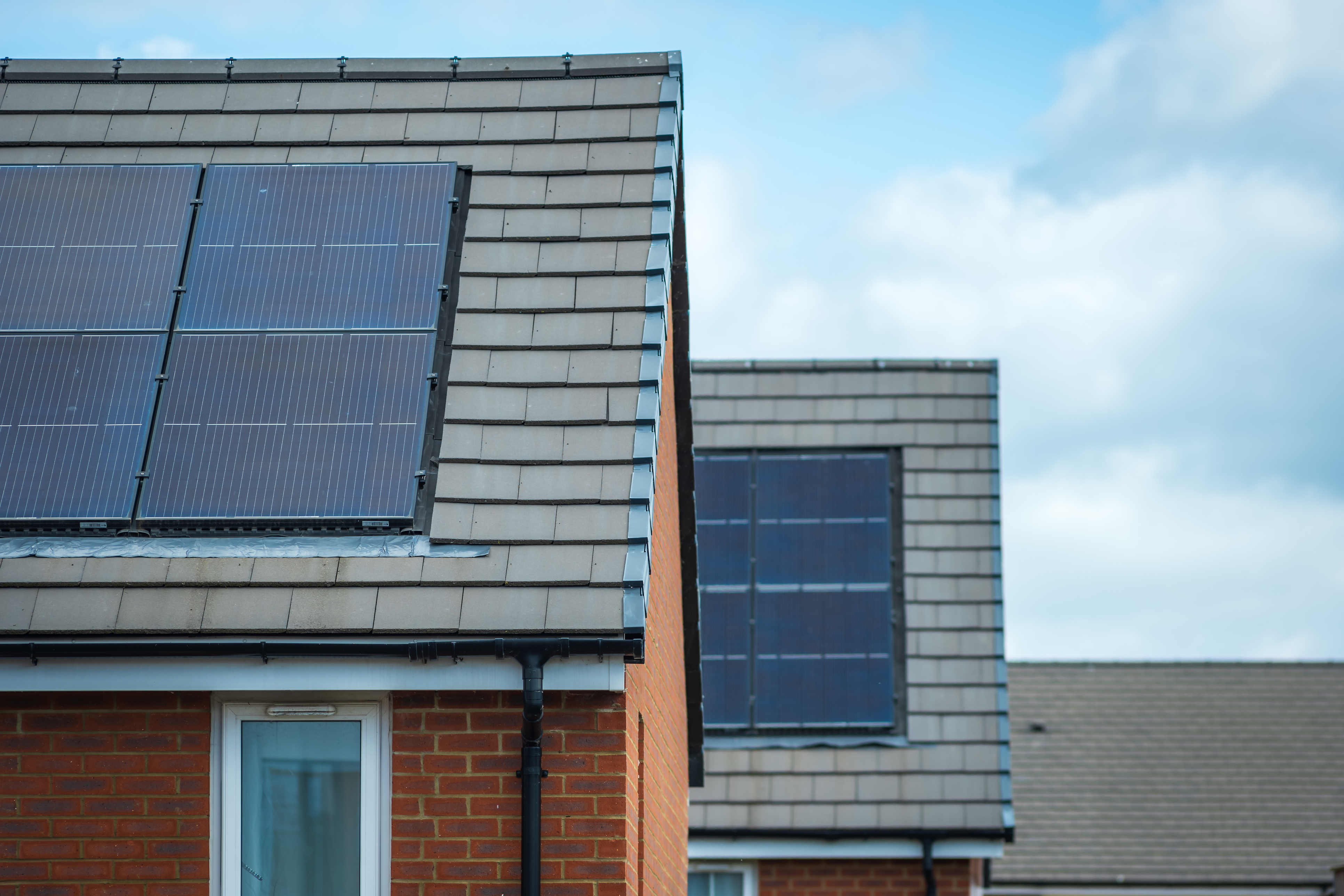 Close-up of the roofs of three new-build homes in a row, with solar panels on each