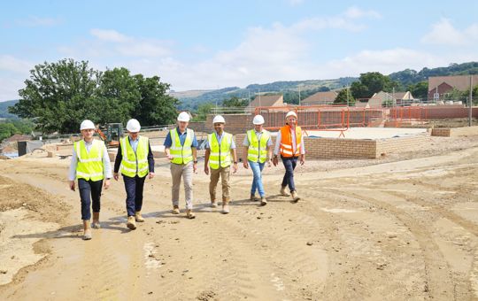 6 men in hi-vis jackets walking through a construction site