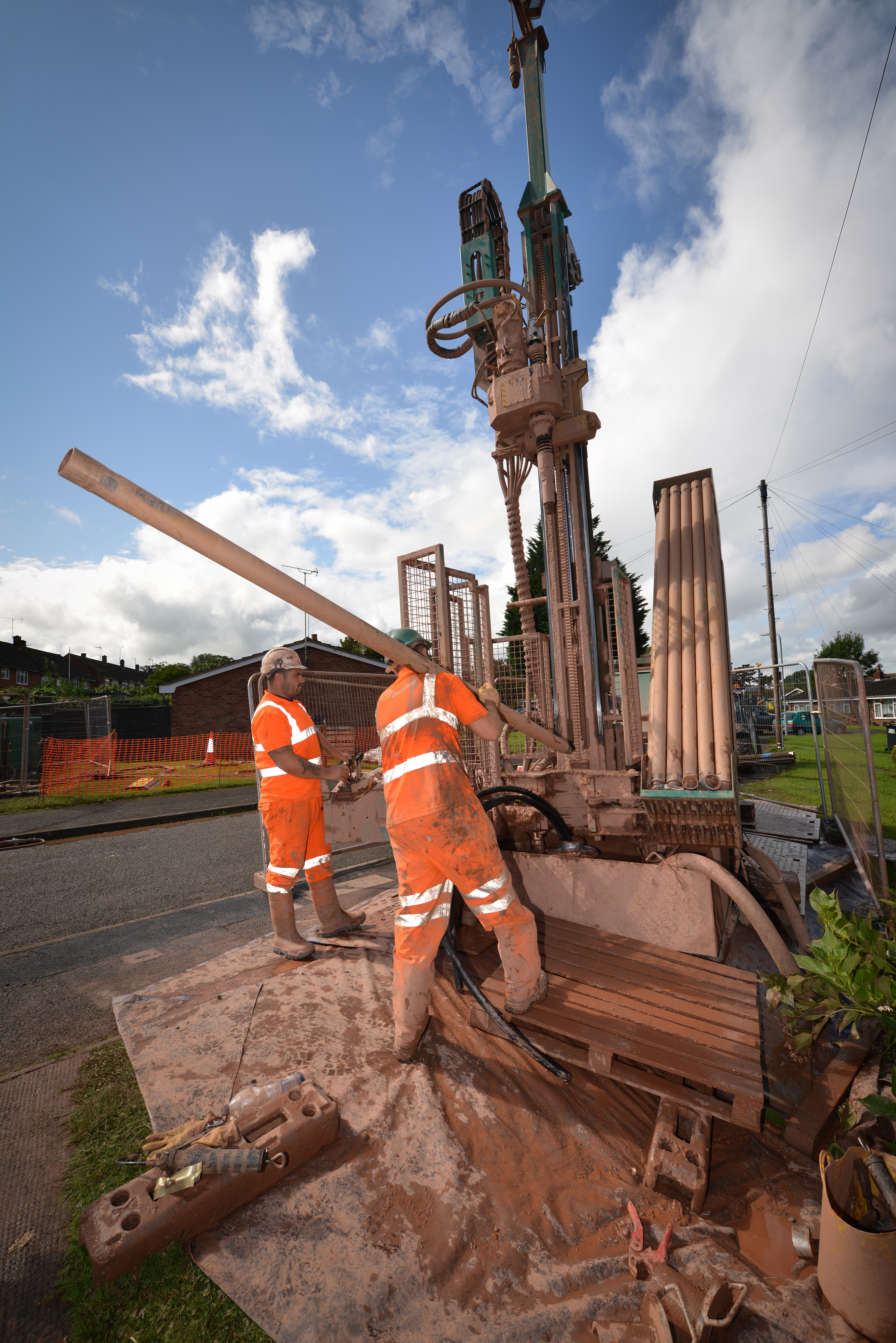 Ground source heat pump being installed by two men in orange hi-vis jackets and machinery