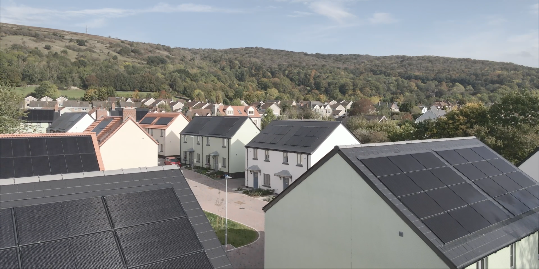 Aerial shot of new-build scheme set in countryside. Homes have solar panels on roofs
